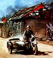 Немецкий мотоциклист едет по горящей русской деревне. Лето 1941 г.